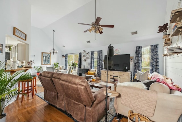 living room featuring hardwood / wood-style floors, ceiling fan with notable chandelier, visible vents, and a wealth of natural light