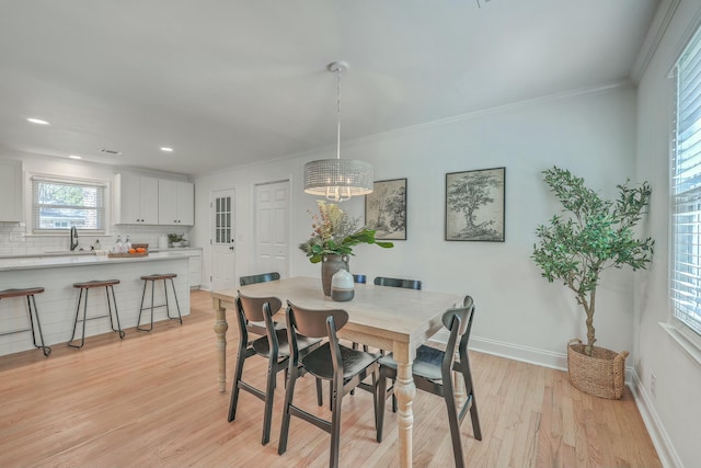 dining room featuring crown molding, light wood-type flooring, and sink