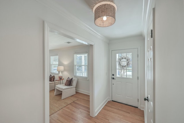 entryway with a wealth of natural light, crown molding, and light wood-type flooring