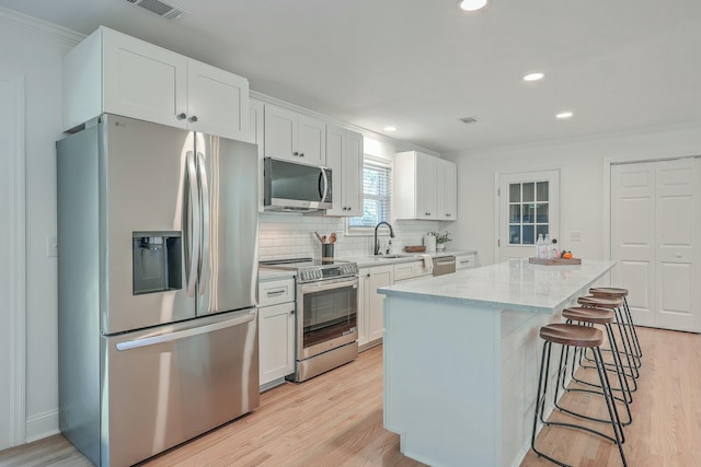 kitchen with a center island, backsplash, sink, white cabinetry, and stainless steel appliances