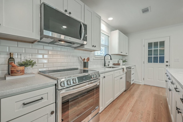 kitchen featuring sink, stainless steel appliances, crown molding, decorative backsplash, and white cabinets