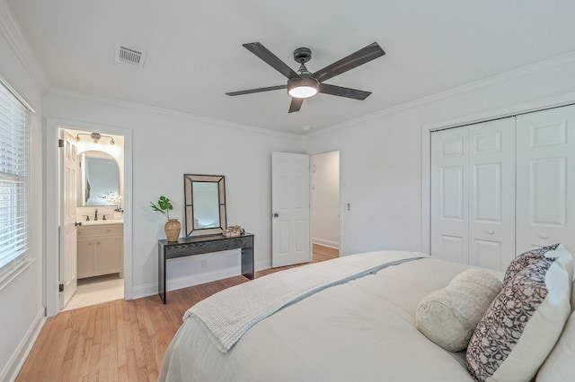 bedroom with ensuite bathroom, ceiling fan, multiple windows, light hardwood / wood-style floors, and a closet