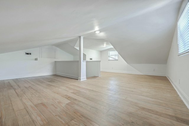 additional living space featuring light wood-type flooring and vaulted ceiling