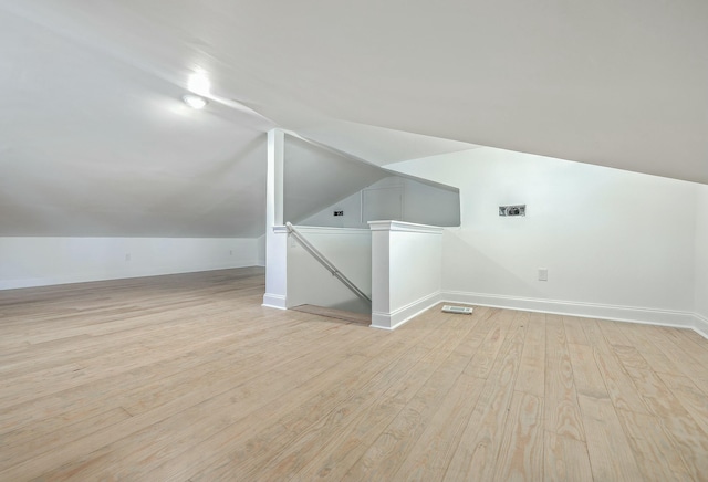 bonus room with light wood-type flooring and vaulted ceiling