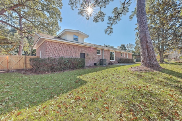 rear view of house featuring a lawn and central AC