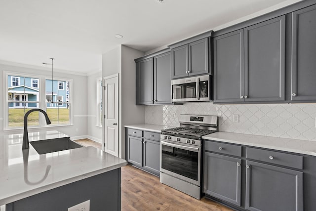 772 Opal Wing St, Moncks Corner, SC 29461 - kitchen featuring appliances with stainless steel finishes, crown molding, gray cabinetry, wood finished floors, and backsplash