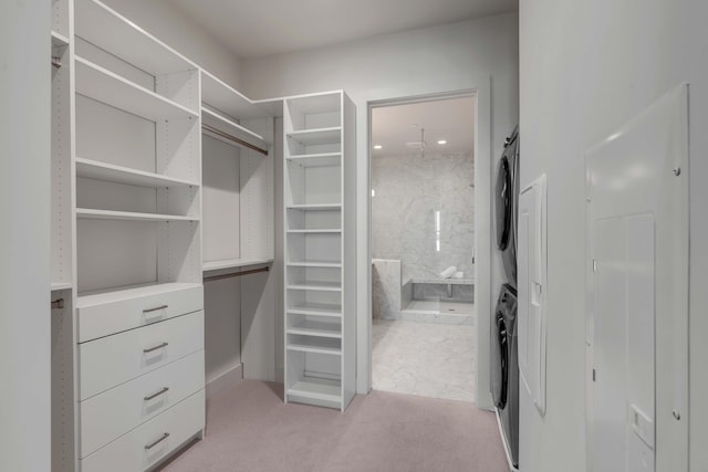 walk in closet featuring stacked washer / drying machine and light carpet