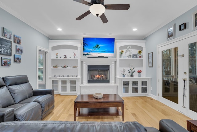 living room with french doors, ornamental molding, built in features, hardwood / wood-style flooring, and ceiling fan