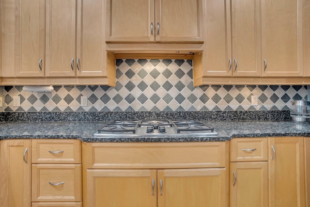 kitchen featuring dark stone countertops, tasteful backsplash, stainless steel gas cooktop, and light brown cabinets