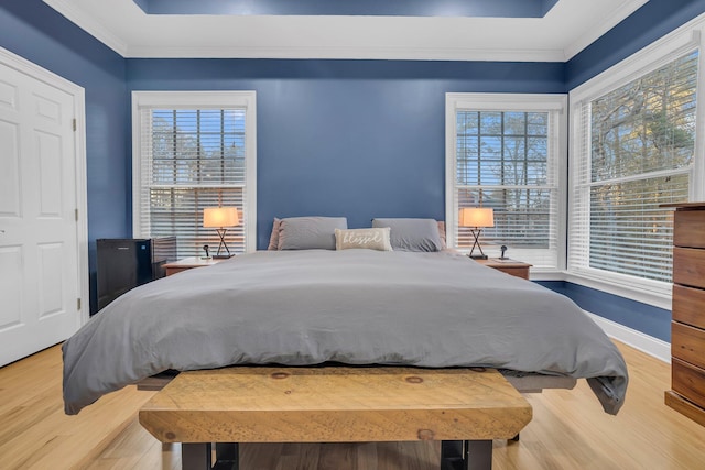 bedroom featuring a tray ceiling, wood-type flooring, and ornamental molding