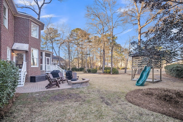 view of yard featuring a sunroom, a playground, a patio area, and a fire pit