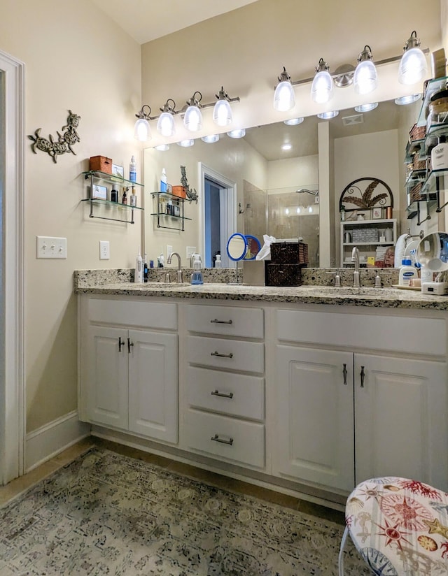 full bathroom featuring a sink, a shower stall, baseboards, and double vanity