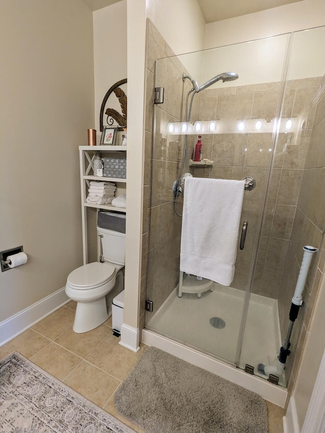 full bathroom with a stall shower, baseboards, tile patterned flooring, and toilet