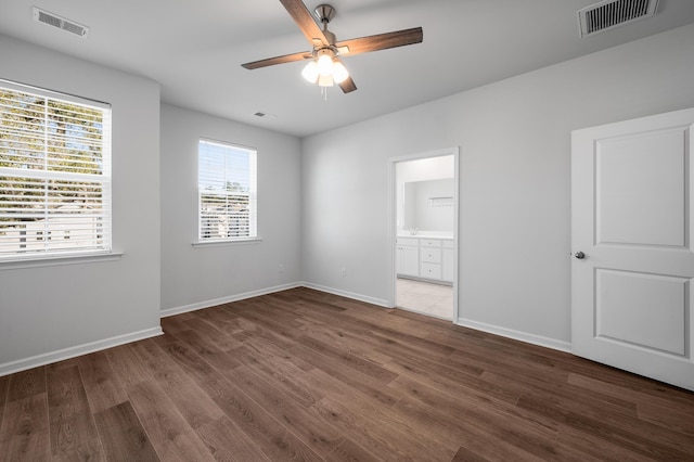 unfurnished bedroom with ceiling fan, dark wood-type flooring, and connected bathroom