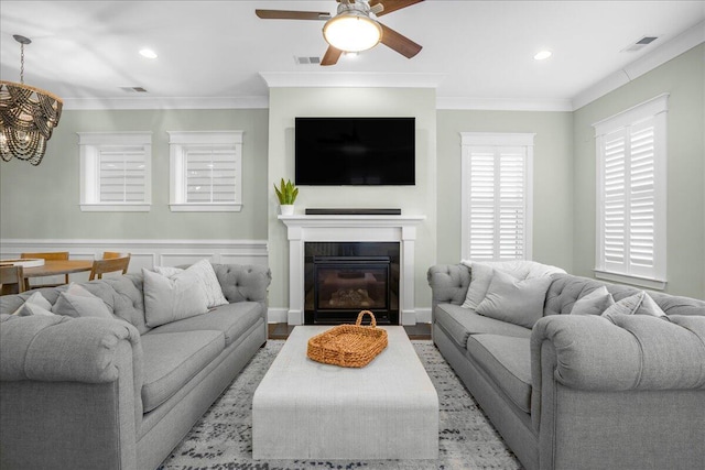 living room with ceiling fan with notable chandelier, visible vents, and ornamental molding