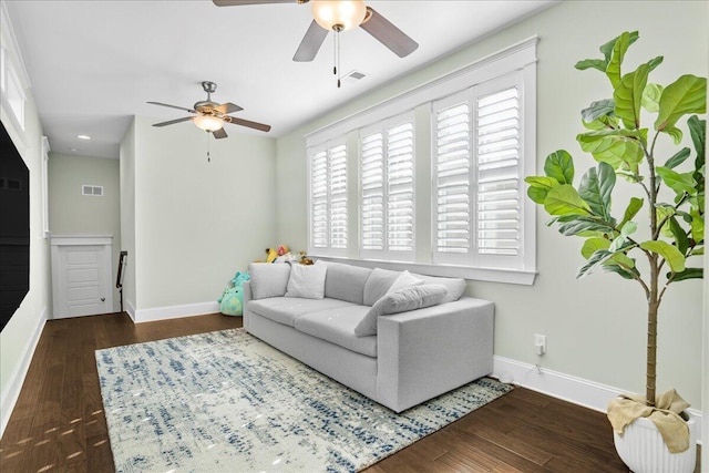 living area featuring visible vents, wood finished floors, baseboards, and ceiling fan