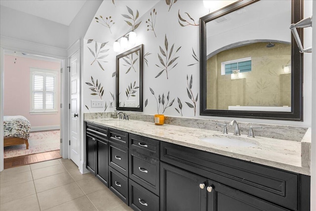 full bath with tile patterned flooring, connected bathroom, baseboards, double vanity, and a sink