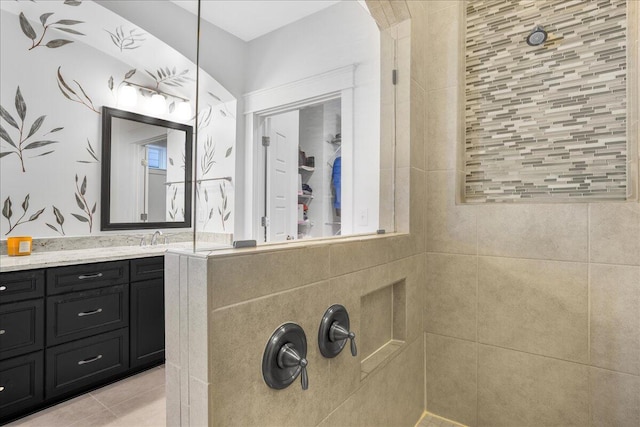 bathroom featuring tile patterned floors, tiled shower, and vanity