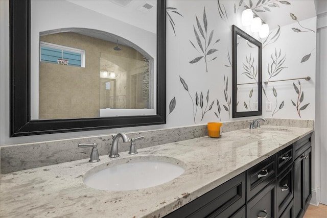 bathroom featuring a sink, double vanity, and a tile shower