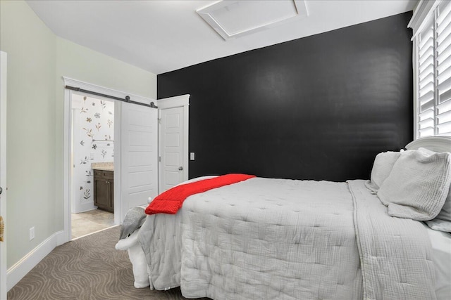 bedroom with ensuite bathroom, a barn door, baseboards, light colored carpet, and attic access