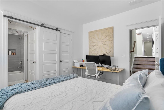 bedroom featuring a barn door, a closet, visible vents, and ensuite bathroom