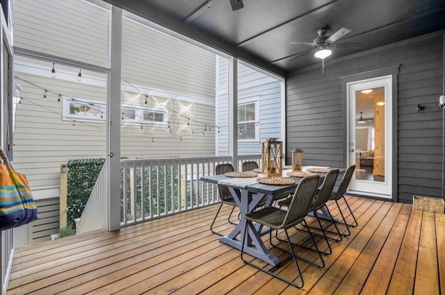 wooden deck with outdoor dining area and a ceiling fan