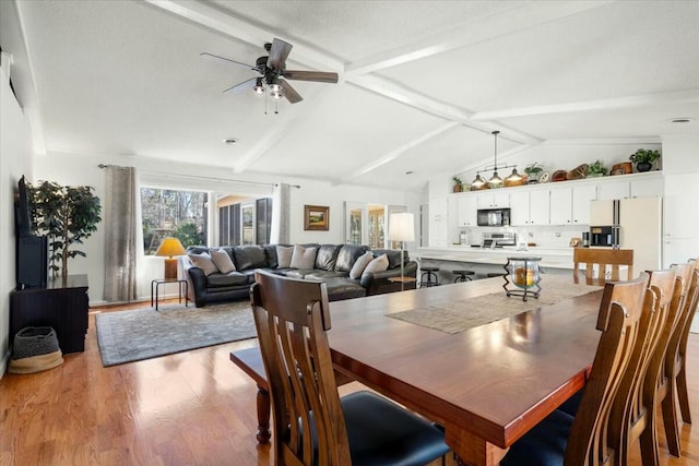 dining space with lofted ceiling with beams, ceiling fan, and light wood-type flooring