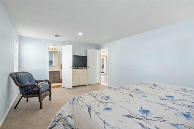 carpeted bedroom with sink, a textured ceiling, and ensuite bath