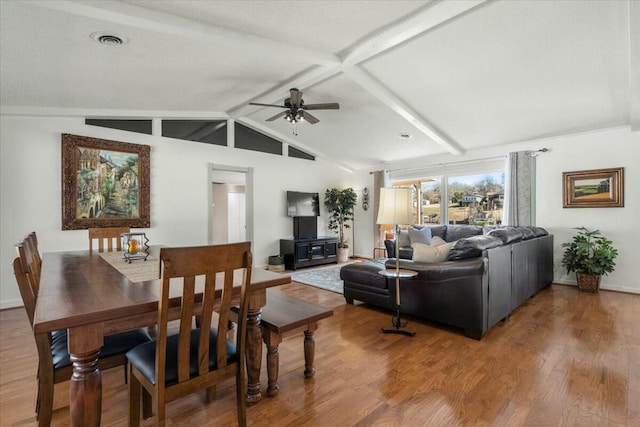 living room featuring ceiling fan, hardwood / wood-style floors, and vaulted ceiling with beams