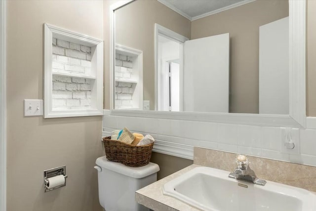 bathroom with tasteful backsplash, sink, ornamental molding, and toilet