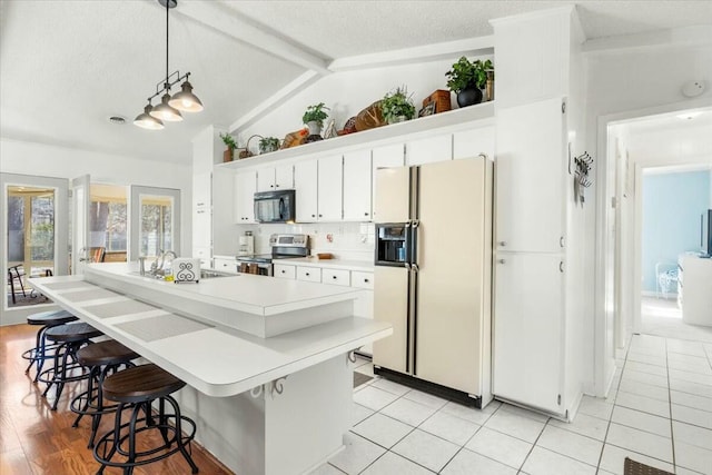 kitchen with sink, stainless steel range with electric stovetop, pendant lighting, white refrigerator with ice dispenser, and white cabinets