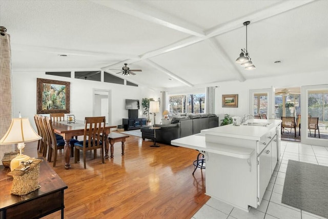 kitchen featuring pendant lighting, sink, lofted ceiling with beams, an island with sink, and white cabinets