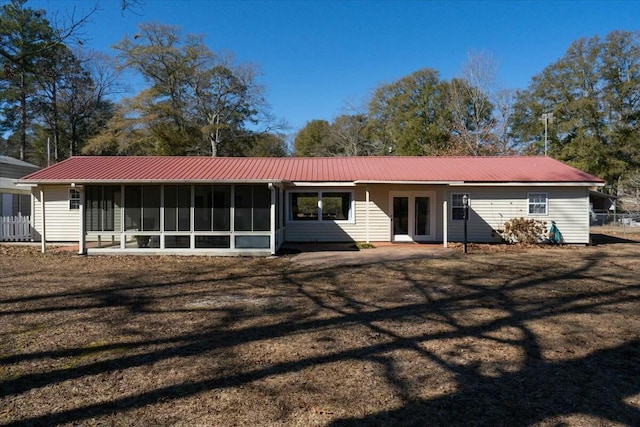 rear view of house featuring a sunroom, a yard, and french doors