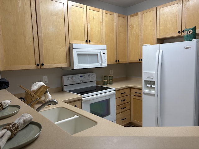 kitchen with white appliances, light brown cabinetry, and sink