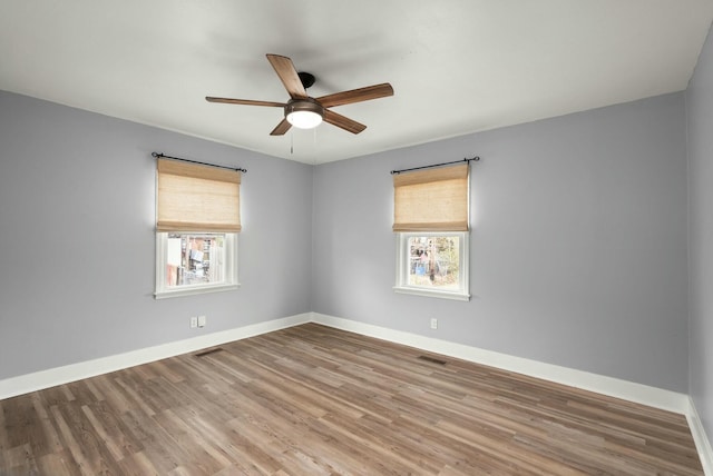 empty room with ceiling fan, hardwood / wood-style floors, and a wealth of natural light