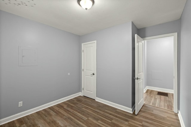 unfurnished bedroom featuring electric panel and hardwood / wood-style flooring