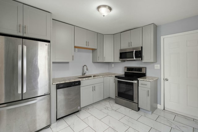 kitchen featuring stainless steel appliances, sink, light stone counters, and gray cabinets