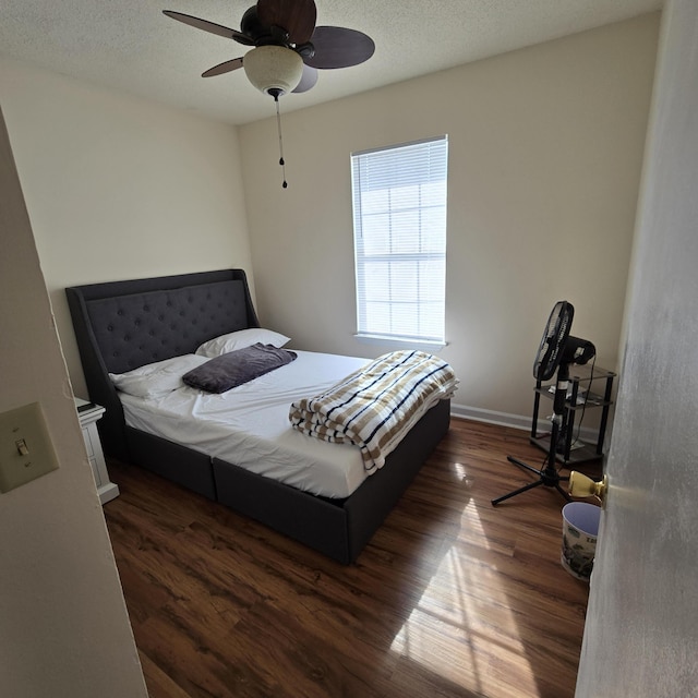 bedroom with ceiling fan, dark hardwood / wood-style floors, and a textured ceiling