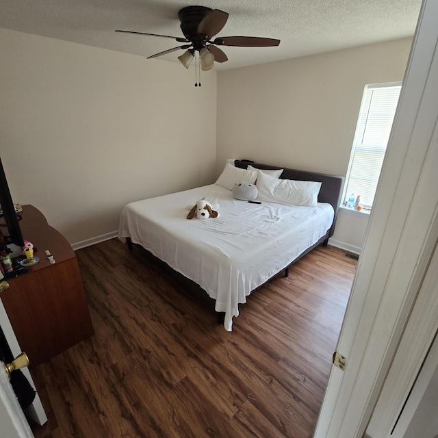 bedroom with ceiling fan, dark hardwood / wood-style floors, and a textured ceiling