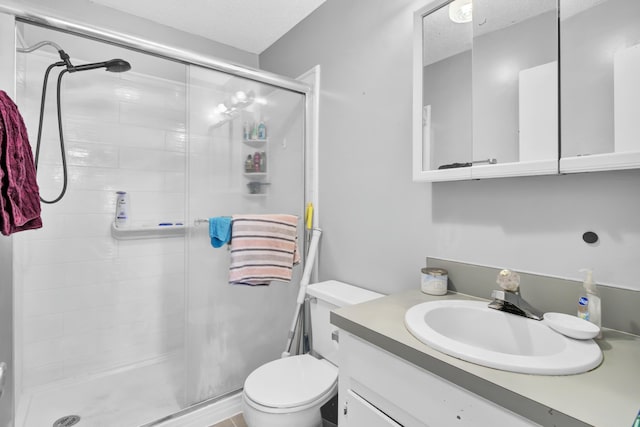 bathroom featuring vanity, a shower stall, toilet, and a textured ceiling