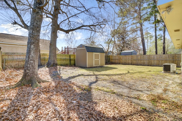 view of yard with an outbuilding, central AC unit, a fenced backyard, and a shed