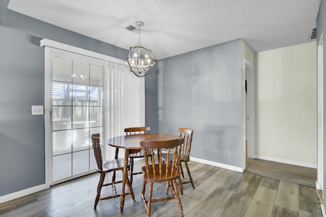 dining space featuring visible vents, a textured ceiling, baseboards, and wood finished floors