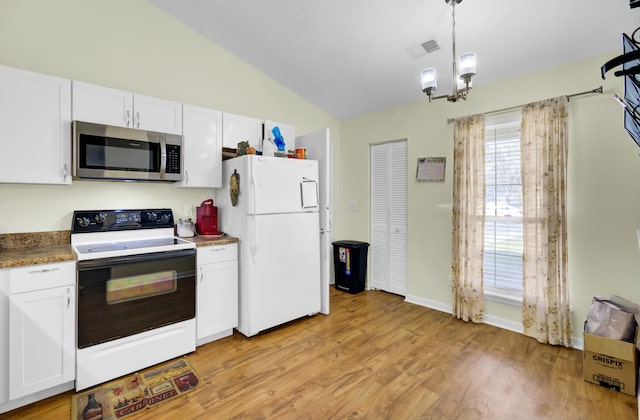 kitchen featuring lofted ceiling, electric range, freestanding refrigerator, white cabinetry, and stainless steel microwave