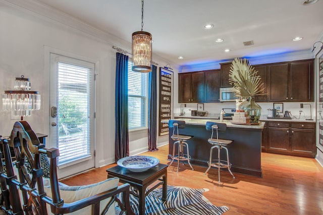 3306 Hartwell St, Johns Island, SC 29455 - kitchen featuring stainless steel microwave, healthy amount of natural light, dark brown cabinets, crown molding, and a center island with sink