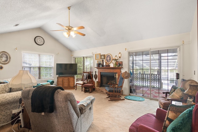 living area with a ceiling fan, lofted ceiling, a textured ceiling, carpet flooring, and a fireplace