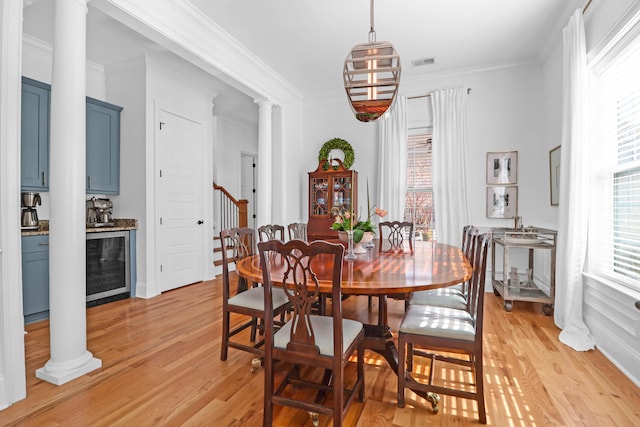 dining area featuring decorative columns, light hardwood / wood-style floors, and a healthy amount of sunlight