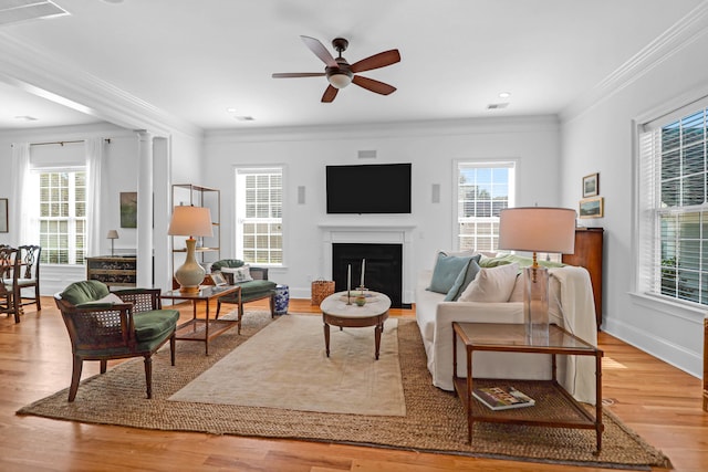 living room featuring ornamental molding, light hardwood / wood-style flooring, ceiling fan, and ornate columns