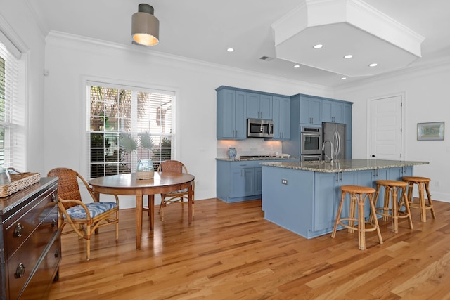 kitchen with ornamental molding, appliances with stainless steel finishes, tasteful backsplash, and light hardwood / wood-style flooring