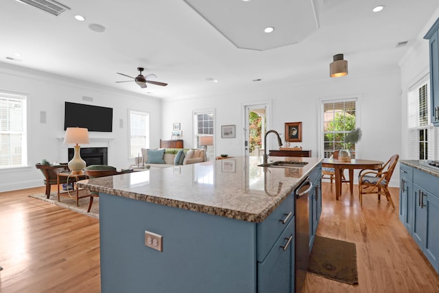 kitchen with an island with sink, light hardwood / wood-style floors, sink, and blue cabinets