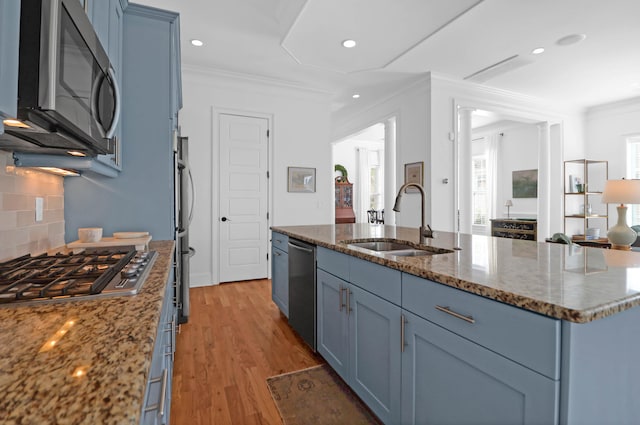 kitchen featuring a kitchen island with sink, appliances with stainless steel finishes, sink, blue cabinets, and light hardwood / wood-style flooring